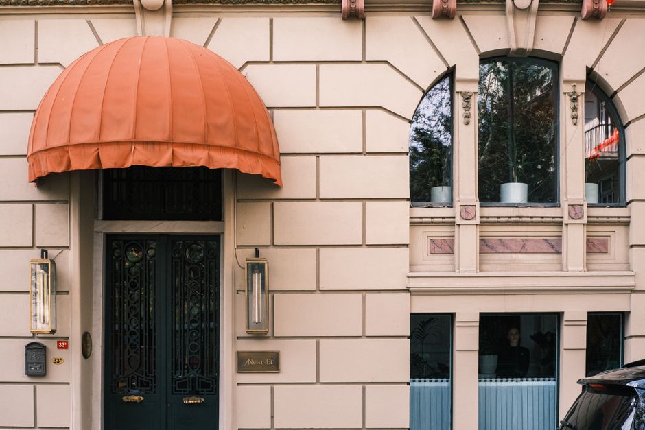 Charming architectural facade with orange awning and arched windows offering a stylish street view.