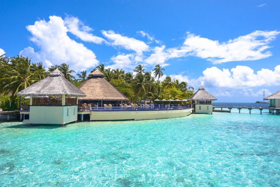 Idyllic overwater bungalows and lush greenery at a resort in Maldives, offering serene tropical paradise views.