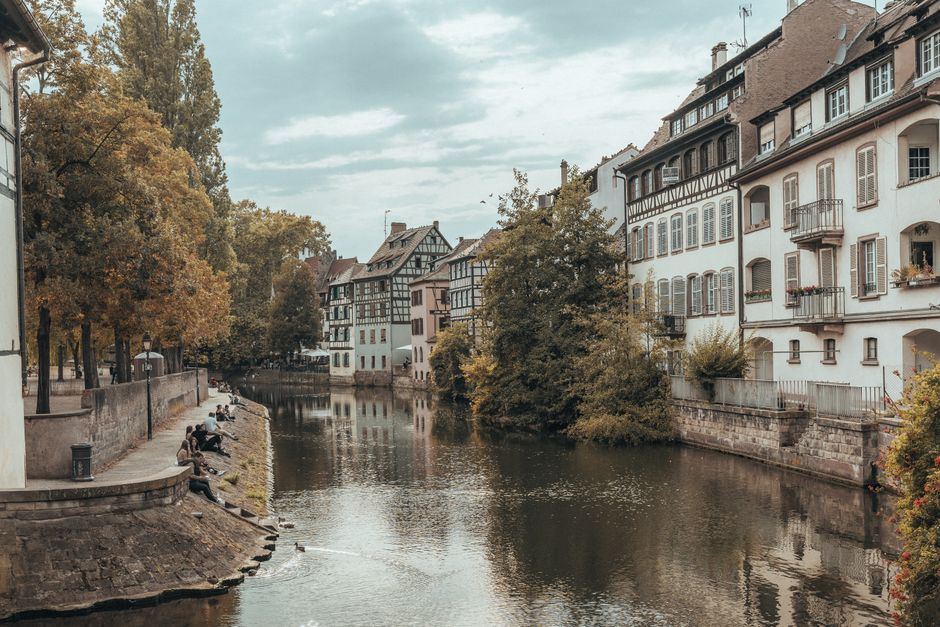 Scenic view of Strasbourg's historic canal lined with quaint buildings and autumn trees.