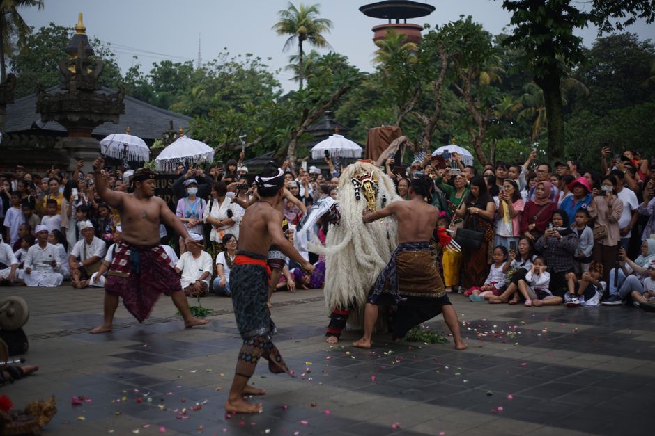 Capturing a vibrant Balinese dance with a lively crowd in a tropical outdoor setting.