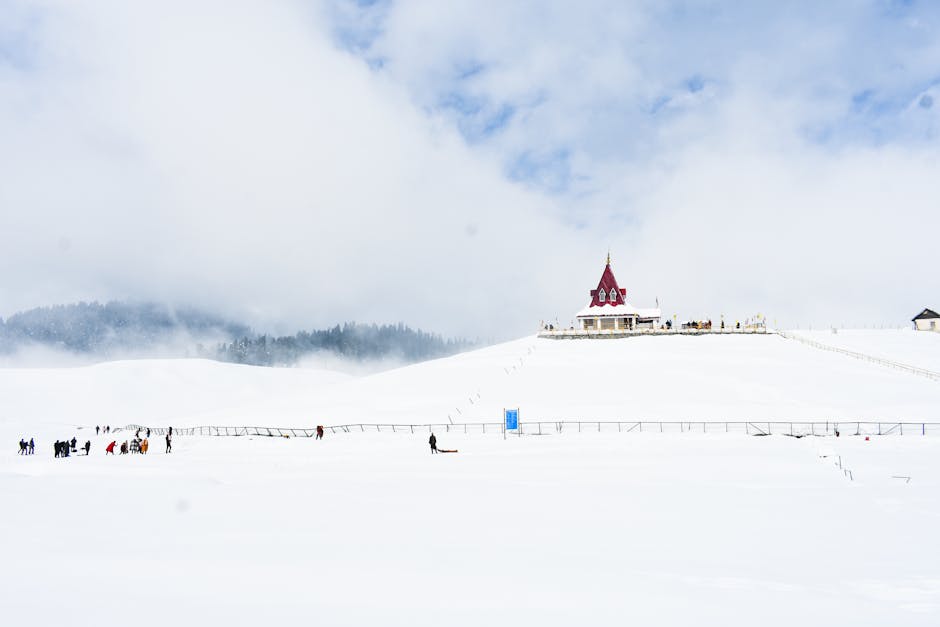 Captivating winter landscape showcasing a snowy hillside with people and a distant architectural structure.