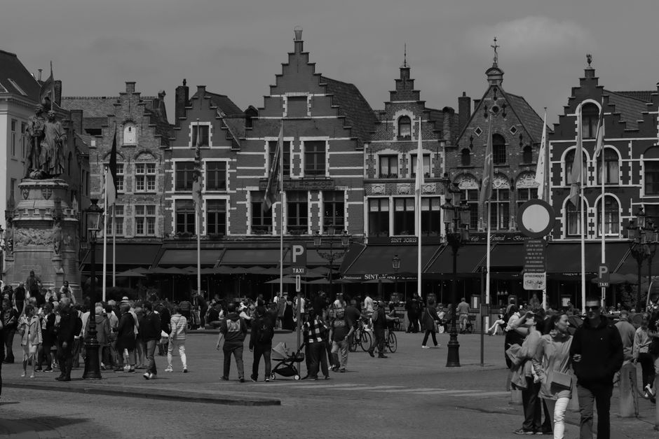 Black and white photo of Bruges Market Square with medieval buildings and a bustling crowd