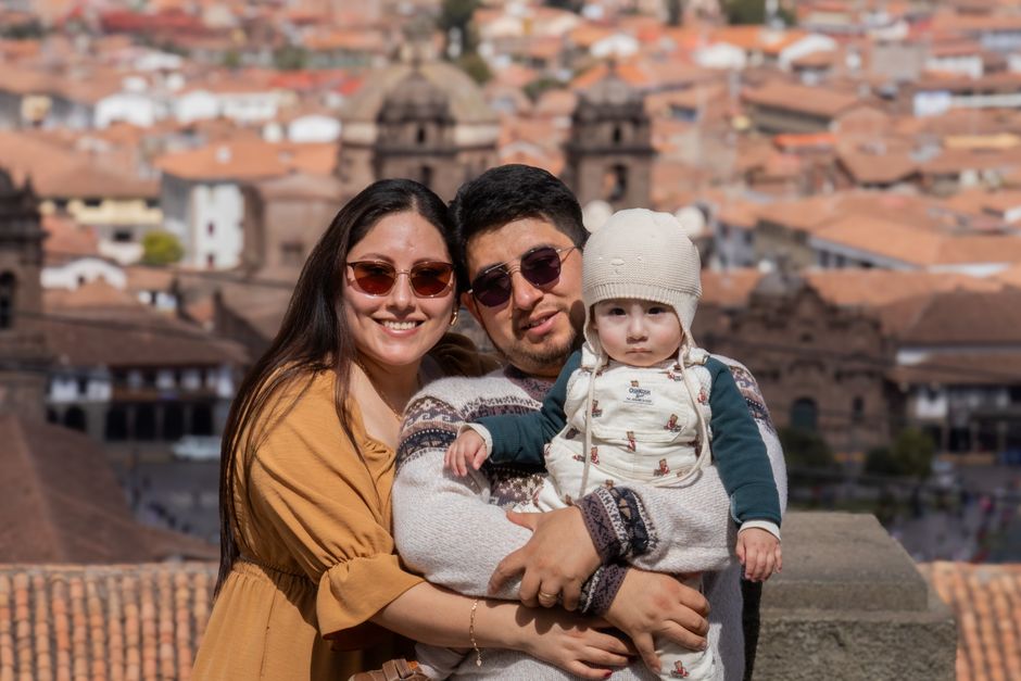 A loving family poses together against a historic cityscape backdrop in warm sunlight.