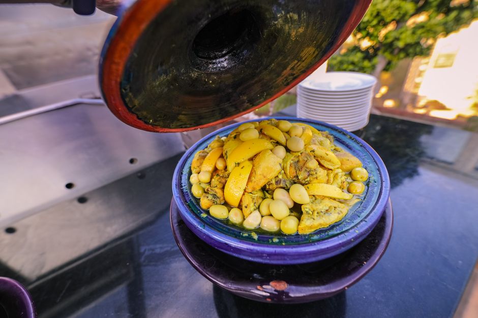 Traditional Moroccan tagine with lemons and olives, served outdoors, showcasing vibrant colors and delicious aromas.