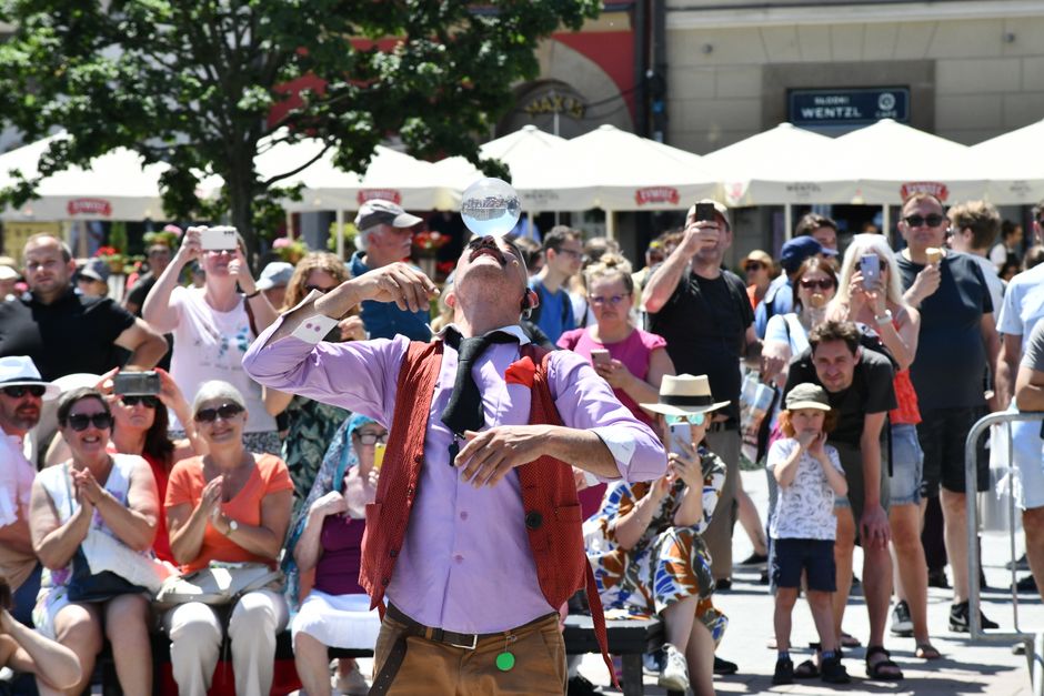 A street performer entertaining a crowd in a lively urban area on a sunny day.