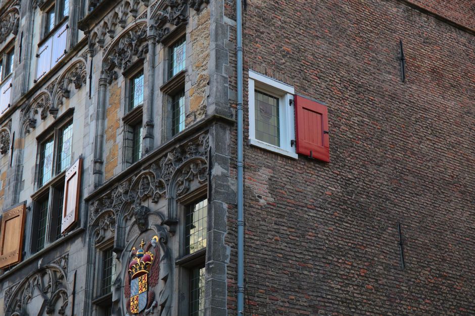 Ornate medieval stone facade with red shutters