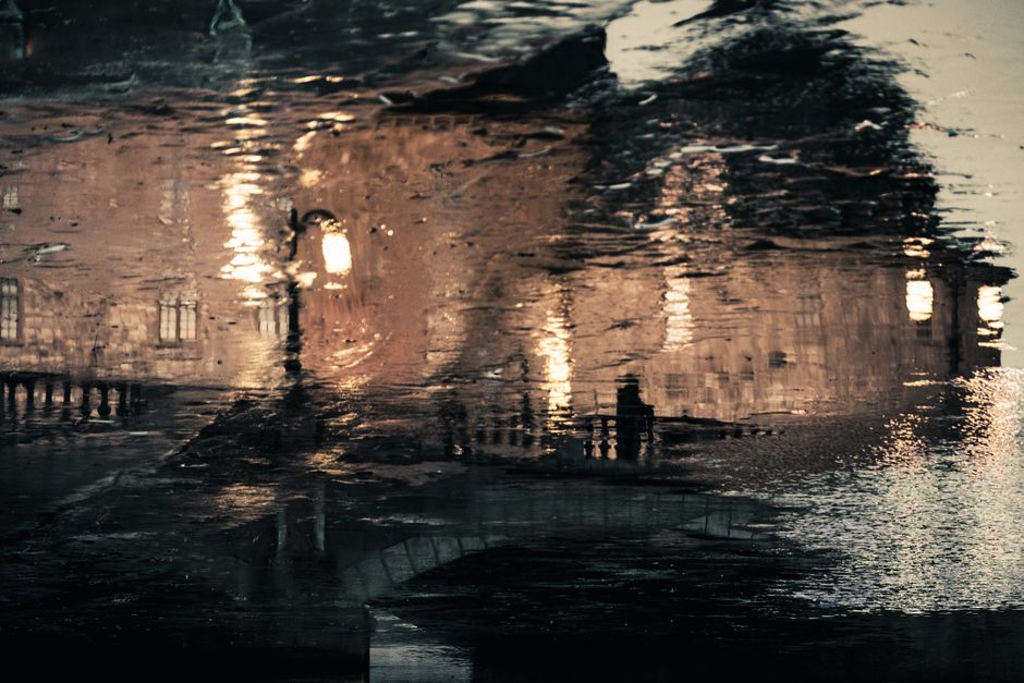 Captivating reflection of street lights and arch bridge at dusk on a tranquil water surface.
