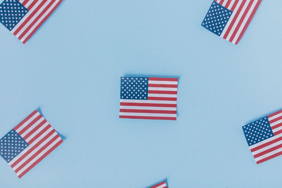Multiple American flags arranged on a pastel blue background for a patriotic theme.