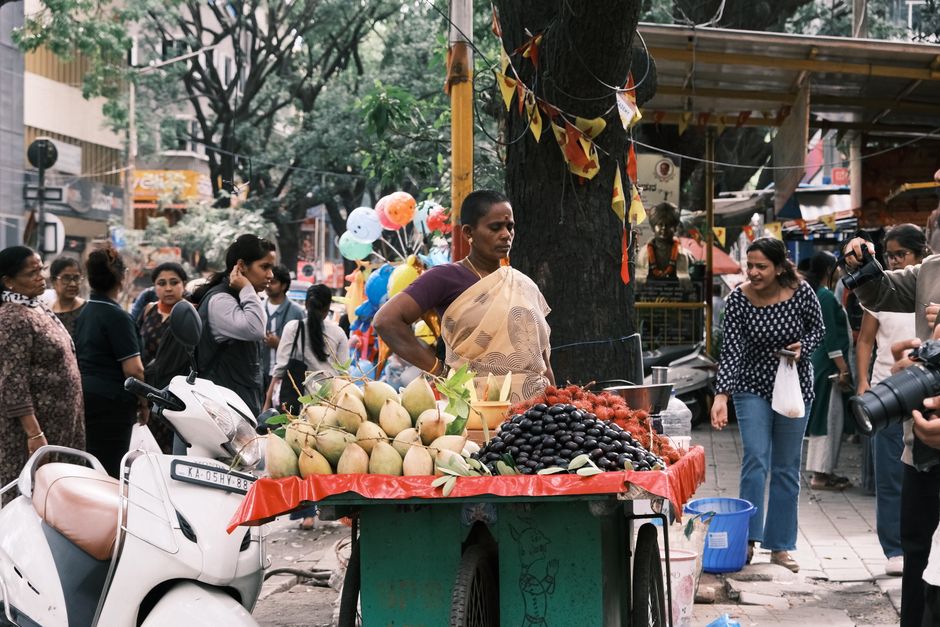 A bustling street market scene in Bengaluru featuring a diverse crowd and fresh produce stall.