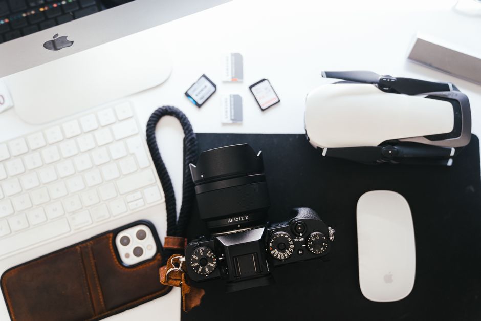 Top view of a photography workspace with camera, drone, keyboard and gadgets for creative professionals.