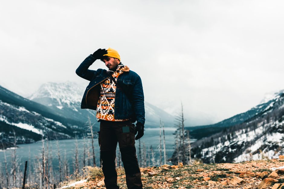 Man poses near snowy lake in Waterton Park, Alberta, showcasing adventure in winter landscapes.