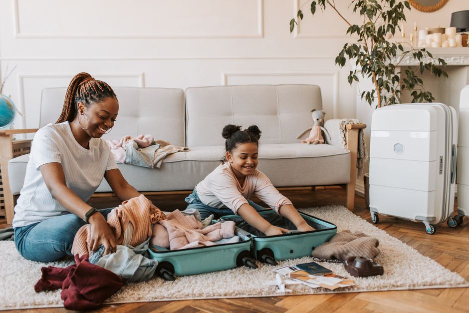 A joyful moment of a mother and daughter packing luggage together in their living room.