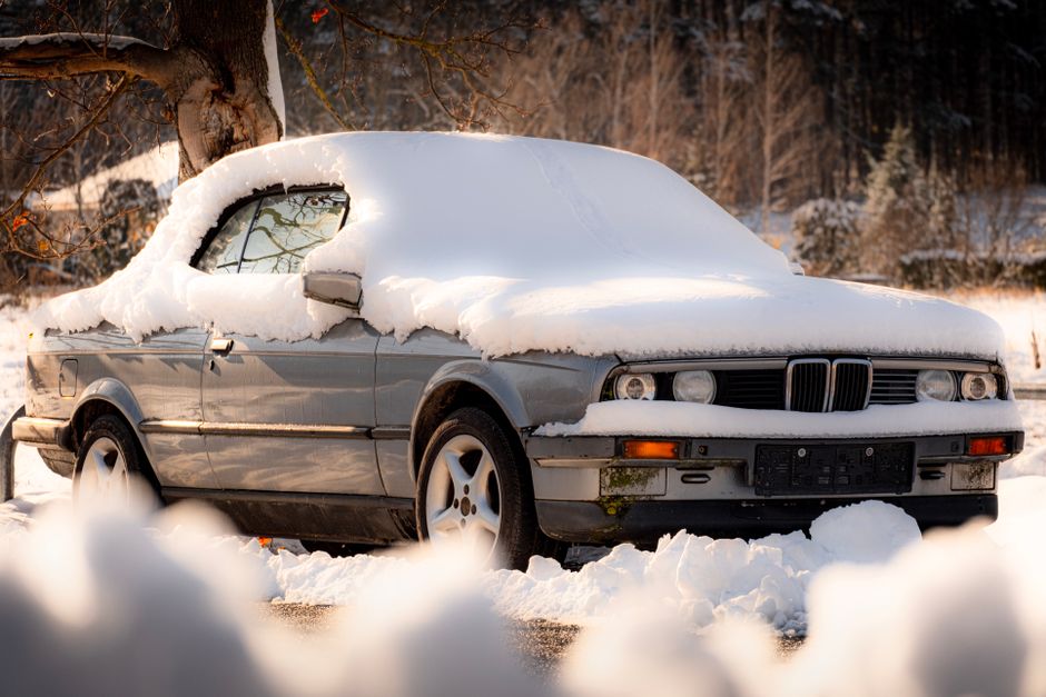 A vintage car is parked under snowfall, covered in snow during winter in Vienna, Austria.