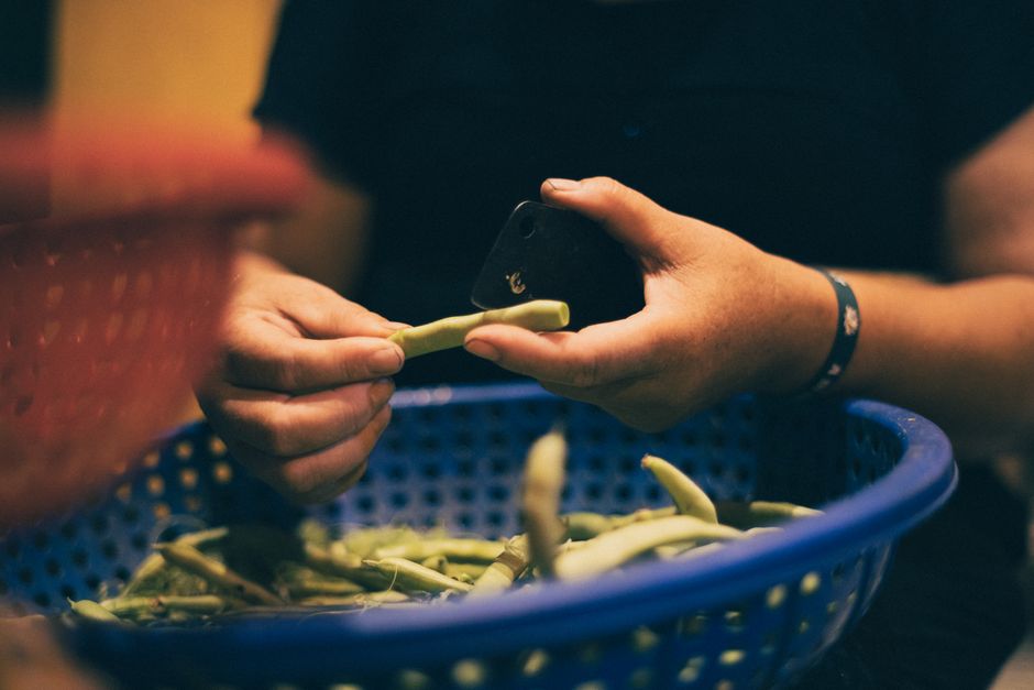 A close-up of hands peeling beans at a traditional market in Hà Nội, Vietnam.