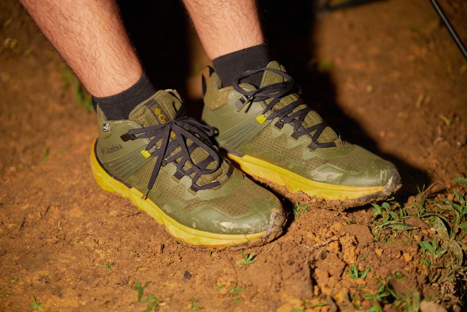 Close-up of green hiking shoes on a muddy trail in Lâm Đồng, Vietnam.