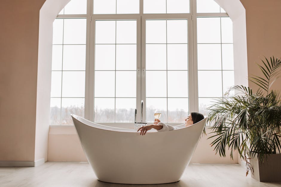 A serene scene of a woman enjoying a glass of wine while relaxing in a modern bathtub indoors.