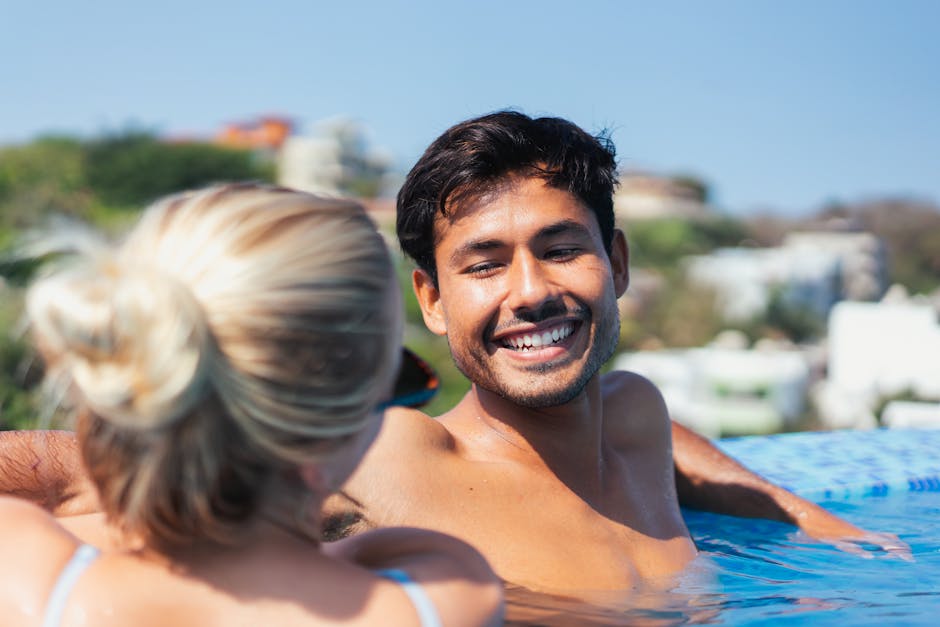 A cheerful couple enjoying a sunny day in an outdoor swimming pool.