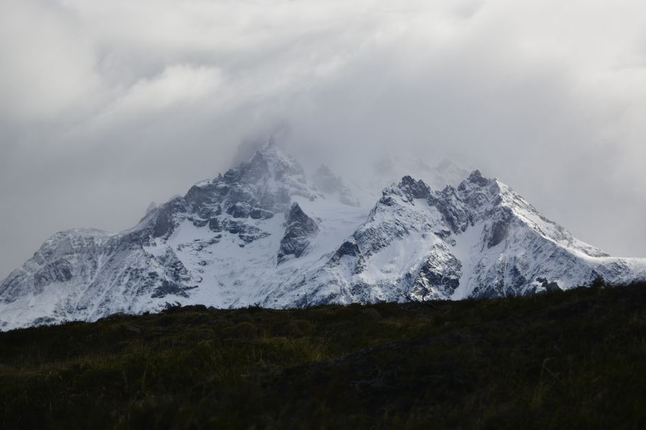 Majestic snow-covered mountains in Torres del Paine, Chile, shrouded in mist.